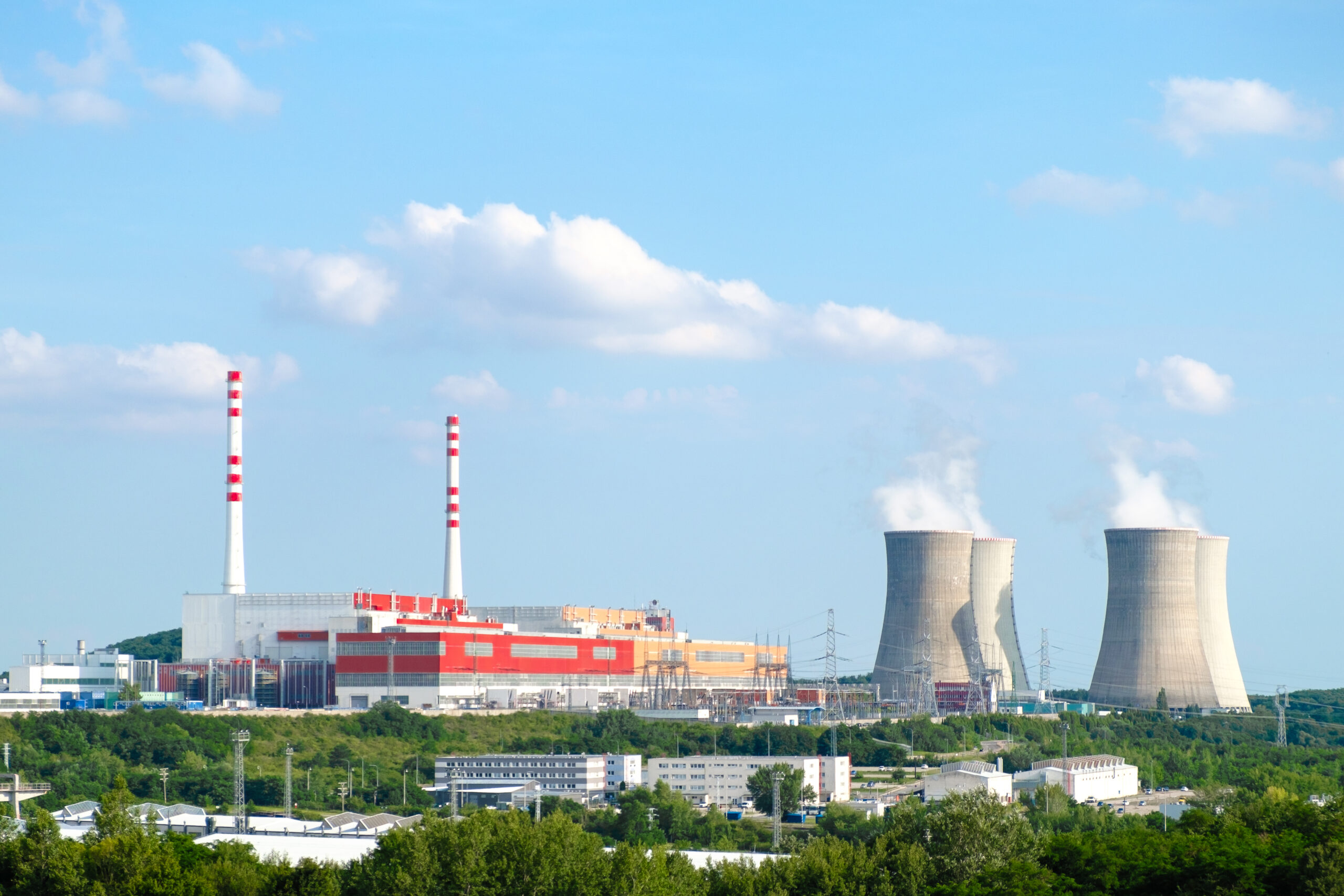 Panoramic view on nuclear power plant with steaming cooling towers on the background of blue sky