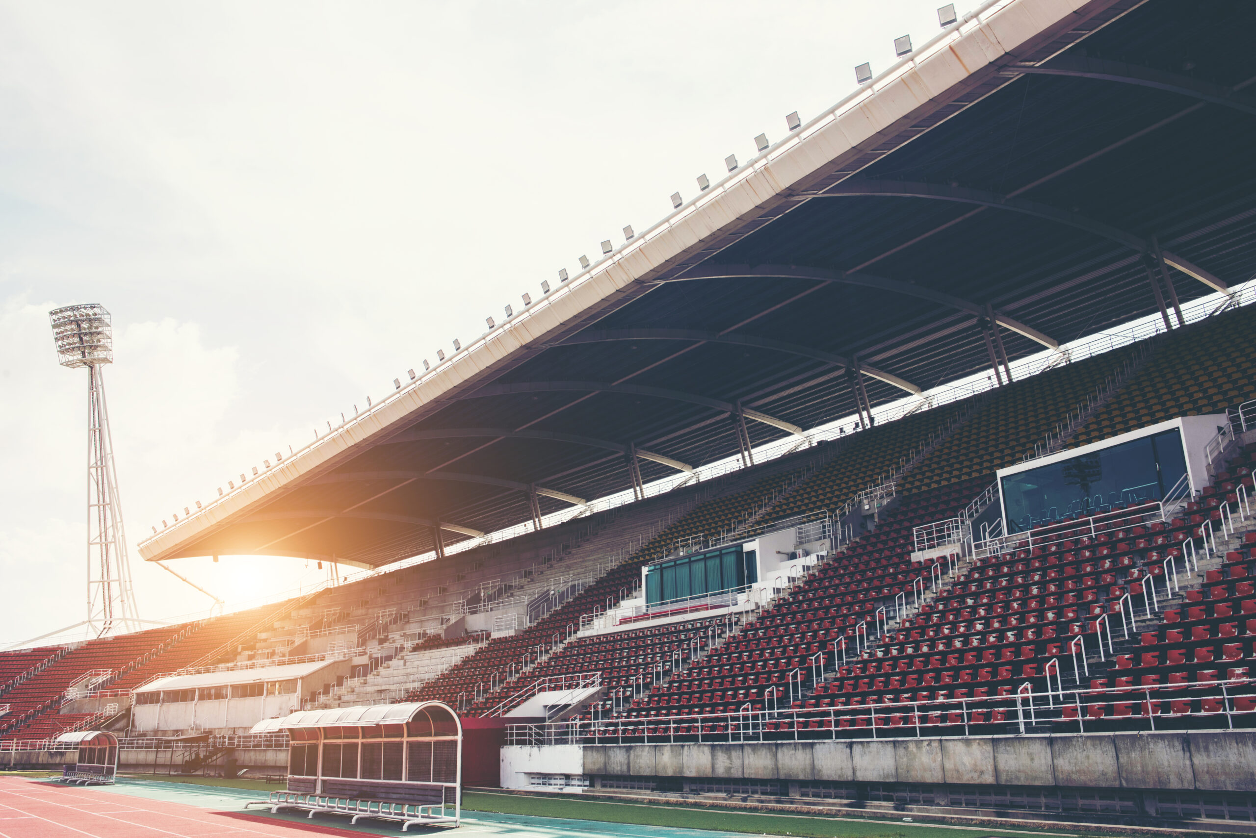 Stadium background with a green grass pitch in the daytime