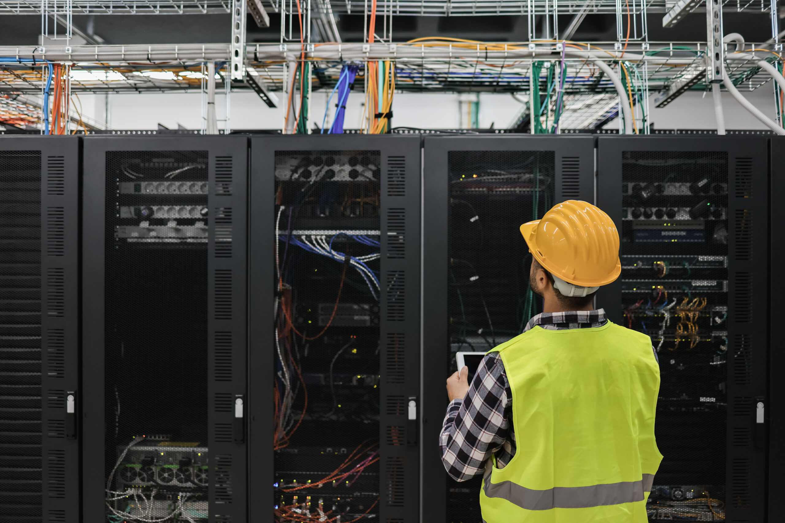 Young technician man working with tablet inside big data center